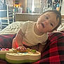 Gabriella is registered to the contest to win money with this photo: baby, child, indoor, toy_guitar, curious, white_shirt, plaid_blanket, furniture, window, natural_light, hand, face, person, playing, cushion, room, soft_light, expression, head_tilt, cozy