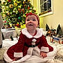 baby, child, christmas_tree, holiday, festive, red_dress, headband, smiling, indoor, decorations, miniature_village, carpet, window, lights, fur_trim, christmas, cute, seasonal, happy, celebration