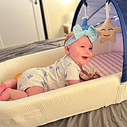 Elena joined the competition — help win amazing prizes! baby, infant, headband, blue_bow, baby_lounger, canopy, star_plush, moon_plush, bed, blanket, smiling, face, crawling, indoor, soft_lighting, clothing, onesie, cute, child, toy