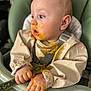 baby, child, closeup, clothing, curious, cute, expression, face, feeding, food, hands, high_chair, indoor, infant, messy, orange_food, portrait, seatbelt, smudged, spoon