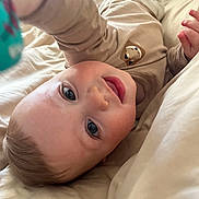 Celio participe au concours pour gagner de l'argent avec cette photo : baby, child, infant, bed, blanket, smiling, face, reaching, cute, clothing, indoors, portrait, happy, skin, head, hand, person, sleepwear, cozy, soft