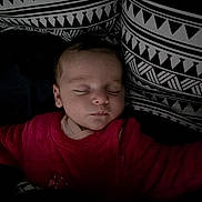 Lynh participe au concours pour gagner de l'argent avec cette photo : baby, sleeping, infant, red_clothing, pillow, patterned_pillow, black_and_white, bed, cozy, peaceful, face, child, portrait, indoor, rest, soft_lighting, young_child, closeup, blanket, candid