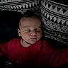 baby, sleeping, infant, red_clothing, pillow, patterned_pillow, black_and_white, bed, cozy, peaceful, face, child, portrait, indoor, rest, soft_lighting, young_child, closeup, blanket, candid