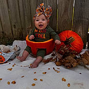 Alanna joined the competition — help win amazing prizes! baby, pumpkin, headwrap, fall, autumn, leaves, smiling, outdoor, wooden_fence, blanket, seed, orange, green_clothing, cute, seasonal, child, festive, happy, sitting, holiday