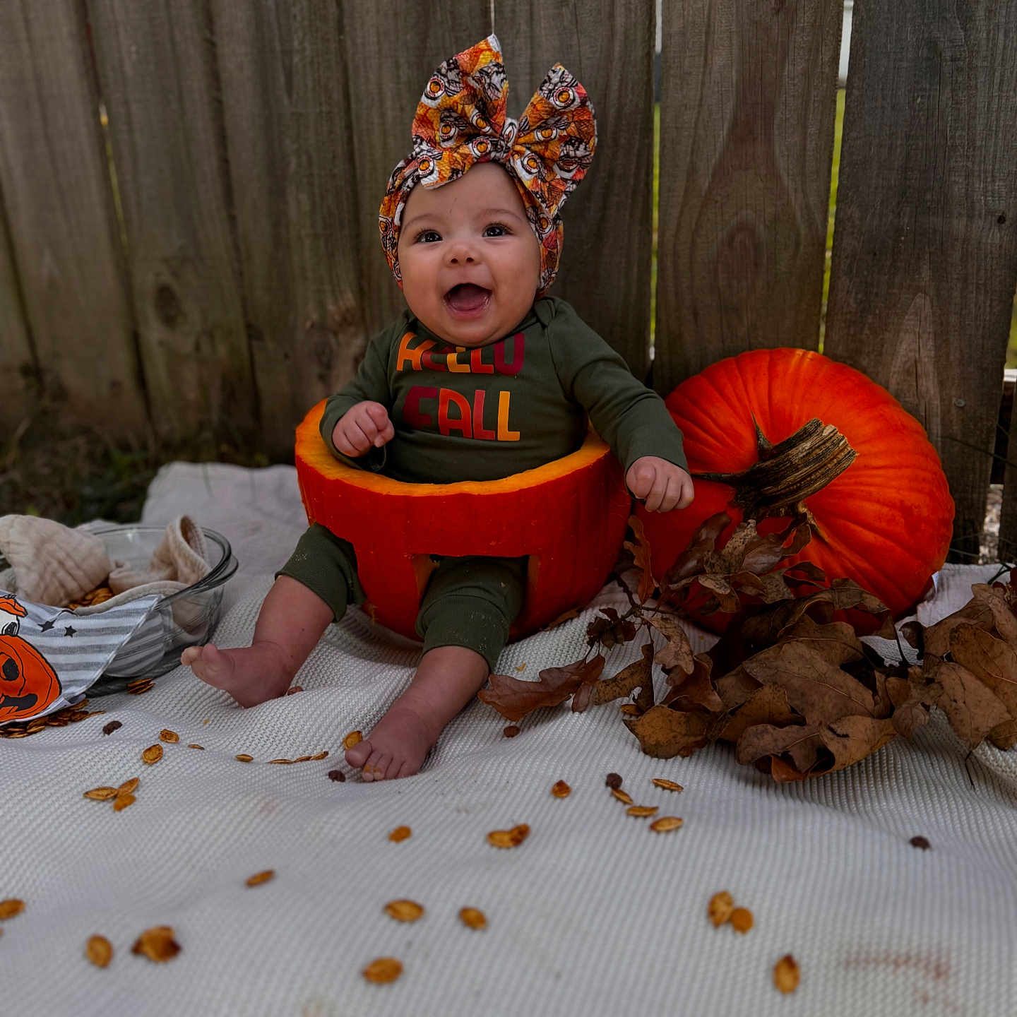 Alanna joined the competition — help win amazing prizes! autumn, baby, blanket, child, cute, fall, festive, green_clothing, happy, headwrap, holiday, leaves, orange, outdoor, pumpkin, seasonal, seed, sitting, smiling, wooden_fence