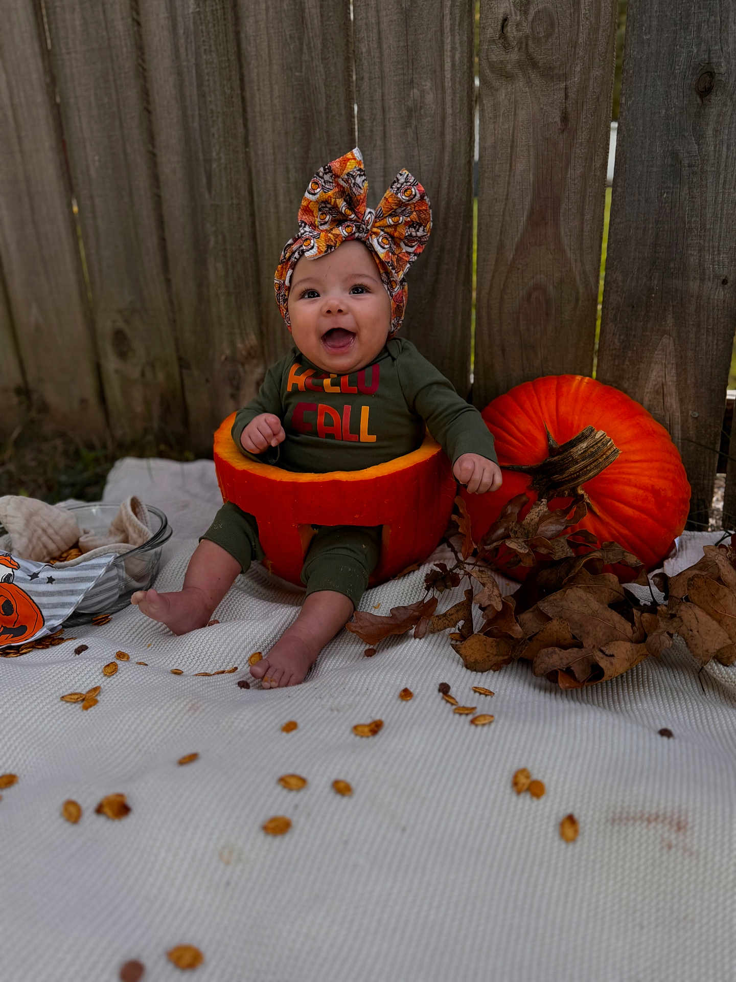 Alanna joined the competition — help win amazing prizes! baby, pumpkin, headwrap, fall, autumn, leaves, smiling, outdoor, wooden_fence, blanket, seed, orange, green_clothing, cute, seasonal, child, festive, happy, sitting, holiday