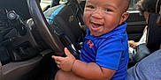 Brian Welch is registered to the contest to win money with this photo: baby, child, smiling, blue_shirt, car, steering_wheel, dashboard, interior, person, seat, window, trees, sunlight, lap, happy, portrait, casual, daytime, vehicle, family