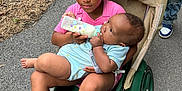 Araelynn Burkett is registered to the contest to win money with this photo: child, baby, feeding, bottle, stroller, outdoor, path, greenery, pink_shirt, blue_onesie, person, sibling, nature, footwear, hand, face, hair, comfort, care, casual_clothing
