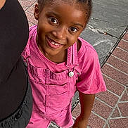 Araelynn Burkett joined the competition — help win amazing prizes! child, smiling, girl, braided_hair, pink_overalls, pink_shirt, outdoor, sidewalk, patterned_pavement, shoes, person, happy, standing, casual_clothing, closeup, portrait, daylight, urban, people, friendship