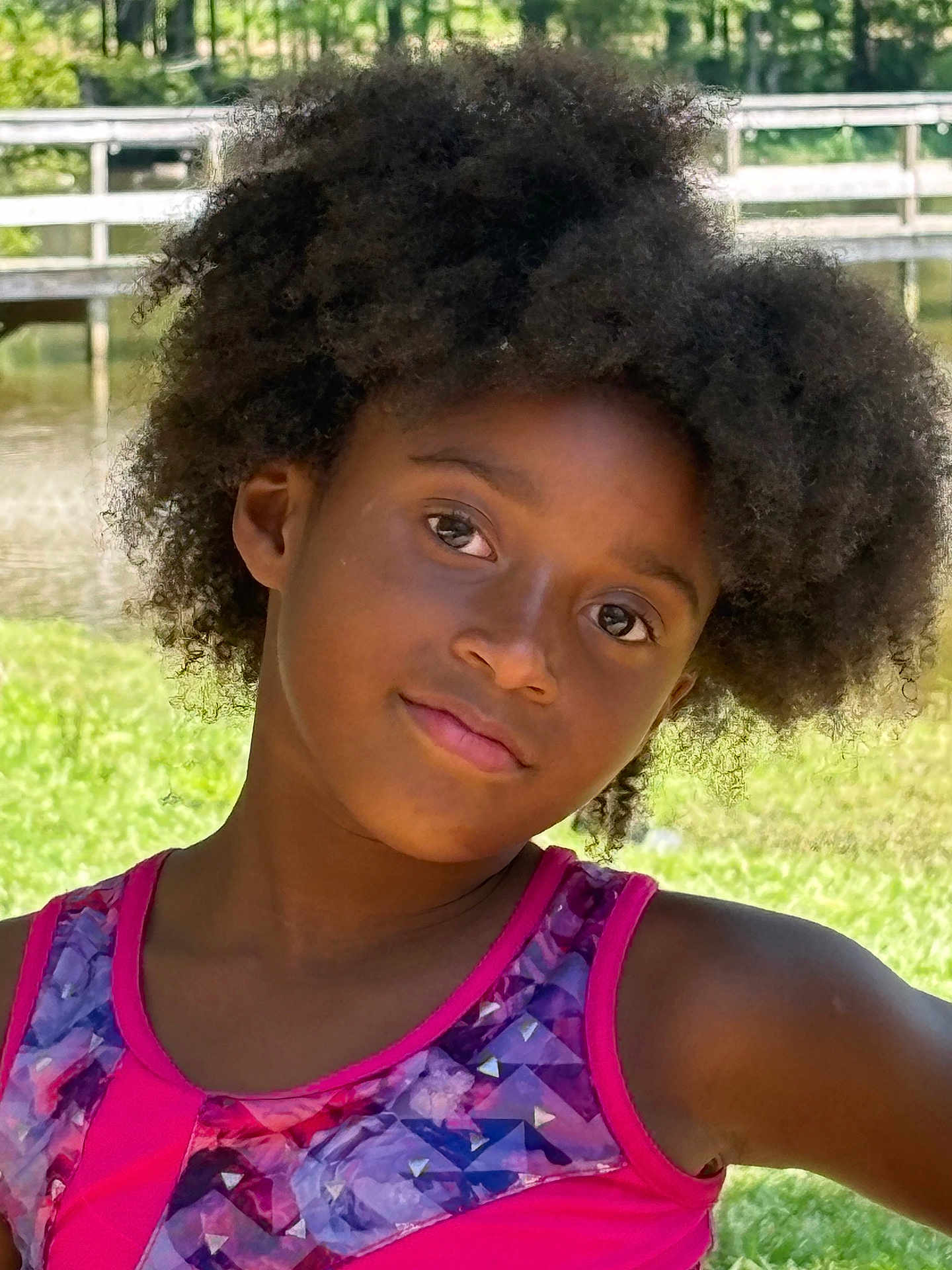 Araelynn Burkett is registered to the contest to win money with this photo: child, afro_hair, outdoor, pond, bridge, greenery, grass, sunlight, portrait, face, smile, tank_top, colorful_clothing, nature, daylight, young_person, casual, summer, happy, relaxing