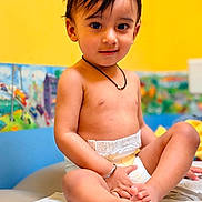 Sahibjot joined the competition — help win amazing prizes! baby, bare_chest, brown_eyes, changing_pad, child, closeup, colorful_background, crossed_legs, dark_hair, diaper, happy, indoors, necklace, nursery, playroom, portrait, sitting, smiling, toddler, wall_art