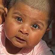 Janhvi participe au concours pour gagner de l'argent avec cette photo : baby, infant, child, portrait, close_up, shaved_head, short_hair, dark_eyes, chubby_cheeks, pink_clothing, earring, hand, blanket, indoor, natural_light, curious_expression, skin, face, parent_partial, tummy_time