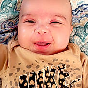 Azula is registered to the contest to win money with this photo: baby, infant, smiling, face, portrait, blanket, patterned_blanket, eyes, mouth, cheeks, tshirt, logo, nike_logo, animal_print, leopard_print, skin, closeup, happy, indoors, cute