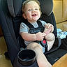 toddler, car_seat, child, smiling, happy, infant, vehicle_interior, seatbelt, black_car_seat, tan_leather, foot, playful, young_child, baby_clothes, sitting, cute, child_safety, car, seat, portrait