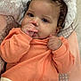 baby, infant, child, thumb_sucking, orange_clothing, seat_belt, cushion, soft_fabric, curly_hair, close_up, portrait, indoor, cute, young_child, resting, comfort, relaxed, baby_clothes, face, hand