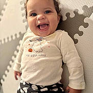 Cataleya is registered to the contest to win money with this photo: baby, child, smiling, happy, face, curly_hair, long_sleeve_shirt, halloween, ghost_print, puzzle_mat, play_mat, infant, cute, indoors, portrait, clothing, toddler, person, expression, fun