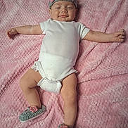 D'Nola is registered to the contest to win money with this photo: baby, blanket, child, cozy, crocheted, cute, footwear, happy, headband, indoors, infant, lying_down, onesie, person, pink, portrait, relaxed, skin, smiling, soft_texture
