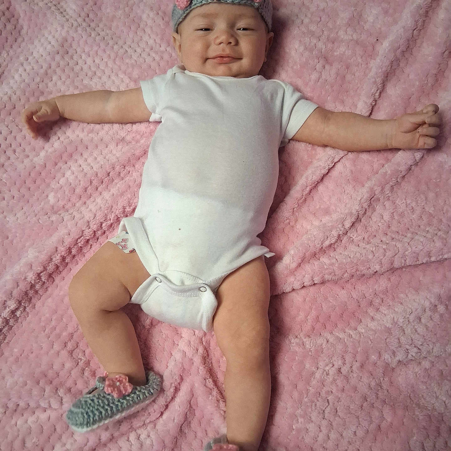 D'Nola is registered to the contest to win money with this photo: baby, blanket, child, cozy, crocheted, cute, footwear, happy, headband, indoors, infant, lying_down, onesie, person, pink, portrait, relaxed, skin, smiling, soft_texture