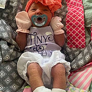 Maielynn joined the competition — help win amazing prizes! baby, infant, pacifier, headwrap, mittens, blanket, quilt, clothing, socks, patterned, pink, white, gray, green, lying_down, cute, sleepy, small, indoors, soft