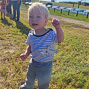 Haigen is registered to the contest to win money with this photo: toddler, child, outdoor, grass, sunny, blue_sky, clouds, striped_shirt, shark_design, celebration, people, adult, casual_clothing, footwear, daylight, nature, field, happy, portrait, fun