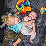 Timothy is registered to the contest to win money with this photo: child, baby, blanket, toy, smiling, happy, sibling, indoor, playing, casual, striped_clothing, camouflage_pants, barefoot, floor, carpet, colorful, patterned_blanket, cuddling, infant, toddler