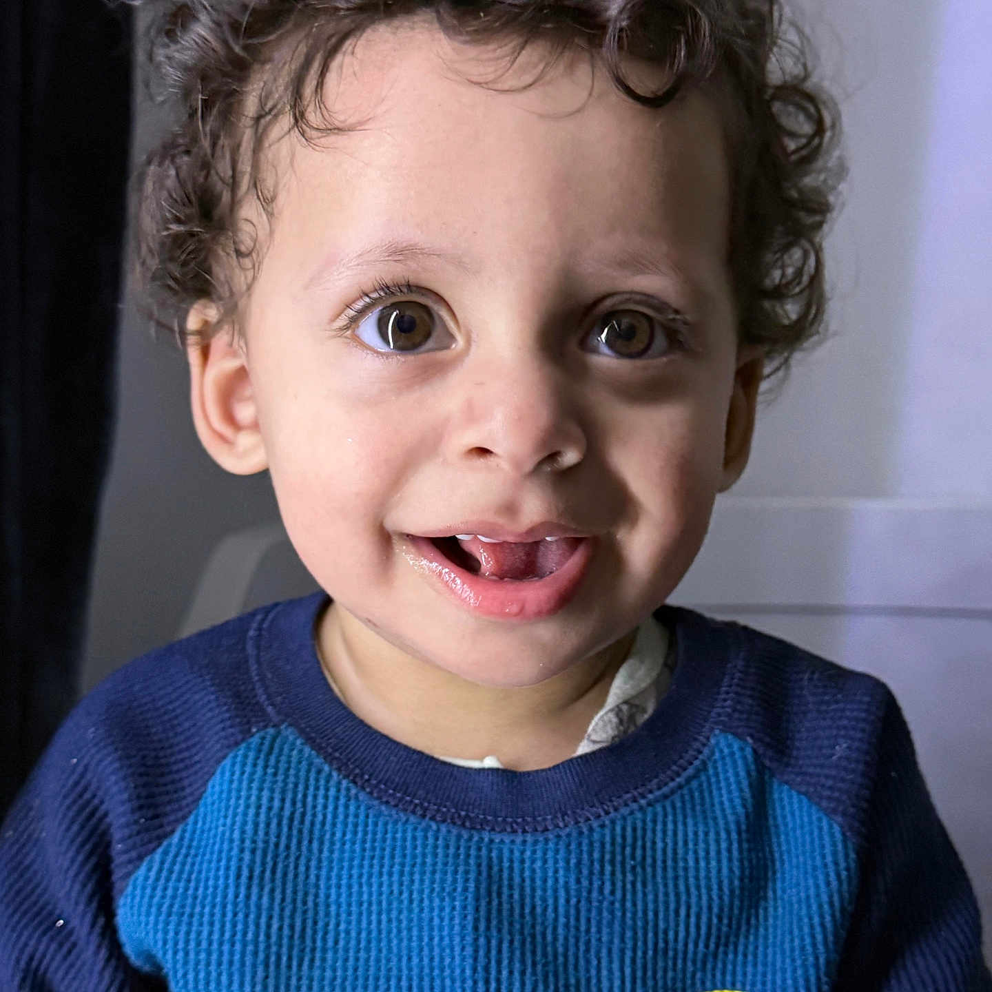 Kenan joined the competition — help win amazing prizes! toddler, child, smiling, curly_hair, blue_sweater, colorful_stripes, indoor, portrait, happy, face, eyes, person, young_child, casual_clothing, vibrant_colors, cute, closeup, expression, warm_lighting, sitting