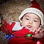 baby, christmas, holiday, lights, red_clothing, santa_hat, cute, festive, infant, playing, colorful_lights, fluffy_blanket, indoors, portrait, closeup, child, holiday_season, celebration, soft_texture, adorable