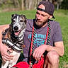 Henty a rejoint le concours — aidez-le/la à gagner de superbes lots ! man, dog, grass, outdoor, pet, canine, happy, casual_clothing, cap, beard, leash, harness, nature, greenery, summer, sunlight, smile, friendship, animal, park