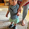 toddler, child, baby, standing, hand_holding, puma_shirt, sneakers, carpet, indoor, adult, legs, feet, shorts, person, support, walking, home, floor, casual_clothing, cute