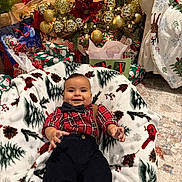 Dylan joined the competition — help win amazing prizes! baby, child, smiling, christmas_tree, christmas_decorations, ornaments, holiday, presents, blanket, plaid_shirt, bow_tie, suspenders, indoors, festive, celebration, carpet, chair, happy, smile, seasonal