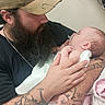 Lila joined the competition — help win amazing prizes! newborn, baby, infant, father, parent, beard, baseball_cap, pacifier, cuddling, holding, family, love, portrait, indoors, hospital, medical_equipment, tattoo, blanket, pink_clothing, tender_moment