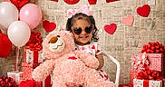 Melani Garcia joined the competition — help win amazing prizes! child, toddler, teddy_bear, heart_shaped_sunglasses, pink_bow, white_chair, valentine_decor, red_hearts, pink_hearts, balloons, gift_boxes, wooden_floor, smiling, indoor, cute, love_banner, pink_shoes, toy_truck, celebration, happy