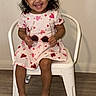 Melani Garcia is registered to the contest to win money with this photo: toddler, child, smiling, sitting, white_chair, heart_pattern, dress, barefoot, indoor, happy, cute, glasses, accessory, young_child, portrait, floor, wall, person, fun, joyful