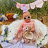 Elena joined the competition — help win amazing prizes! baby, child, sunglasses, party_hat, teddy_bear, plush_toys, flowers, outdoor, grass, banner, celebration, pink_clothing, cute, sitting, nature, footwear, decorations, happy, portrait, grass_field