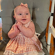 Ally is registered to the contest to win money with this photo: baby, child, dress, headband, chair, cushion, clapping, happy, indoors, smiling, person, cute, infant, seated, pink, skin, young, furniture, portrait, baby_girl