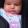 baby, infant, child, car_seat, pacifier, portrait, face, eyes, hair, floral_clothing, dinosaur_pattern, pink, white, seated, indoors, vehicle, close_up, adorable, baby_carrier, photography