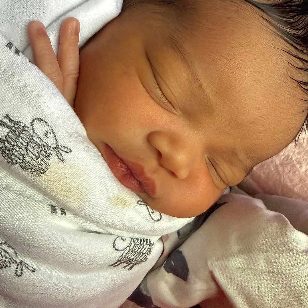 Rayelle is registered to the contest to win money with this photo: baby, blanket, child, closeup, clothing, comfort, cute, face, head, indoors, infant, newborn, peaceful, person, rest, skin, sleeping, soft, tiny_hand, wrapped