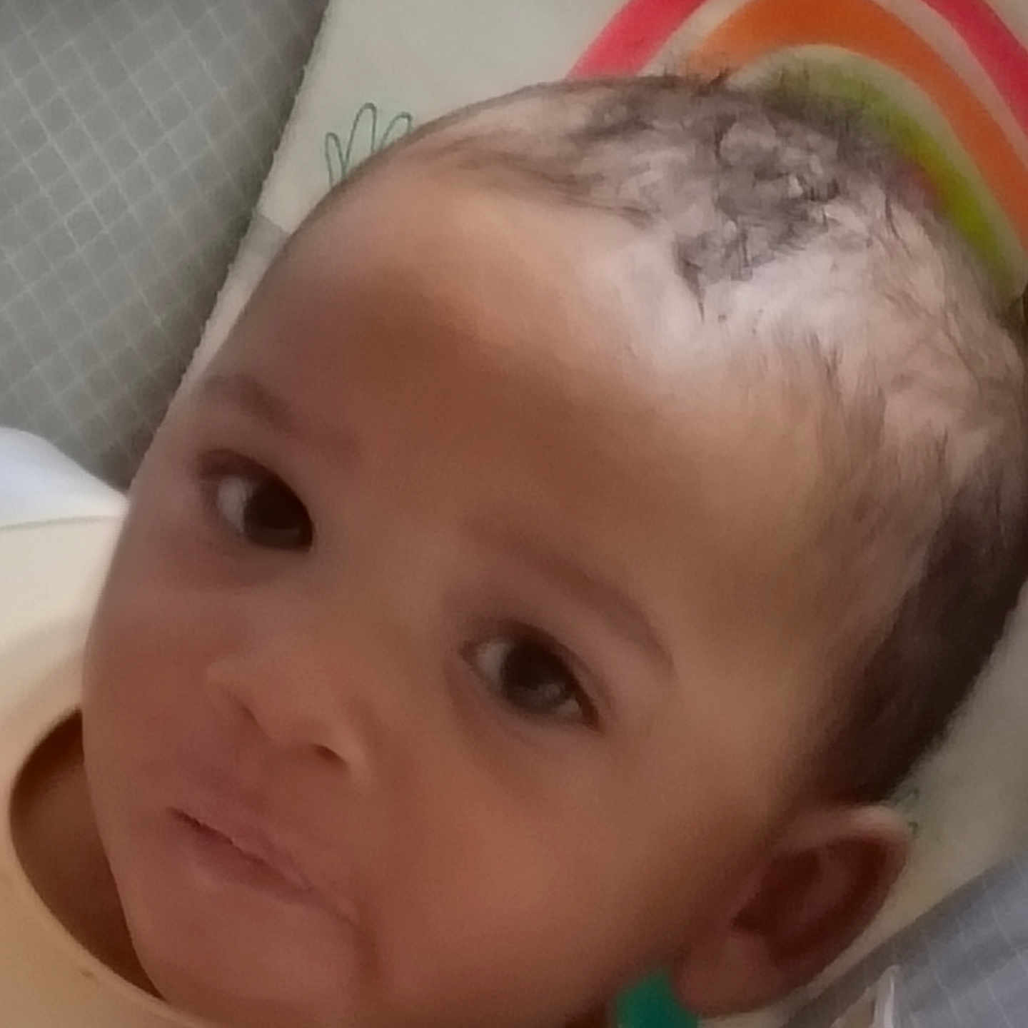Mason joined the competition — help win amazing prizes! baby, infant, face, close_up, portrait, child, cute, eyes, skin, head, hair, expression, resting, pillow, colorful, rainbow, indoors, young, person, soft_focus