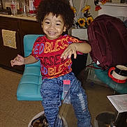 Jonas joined the competition — help win amazing prizes! toddler, child, smiling, curly_hair, red_shirt, blue_jeans, chair, kitchen, sunflowers, backpack, glass_table, mug, happy, indoor, portrait, furniture, floor, cabinet, countertop, houseplant