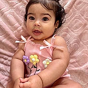 Ailana Martinez is registered to the contest to win money with this photo: baby, blanket, bows, child, clothing, curious, cute, flowers, hands, indoors, infant, knitted, legs, pigtails, pink, portrait, sitting, skin, smiling, soft