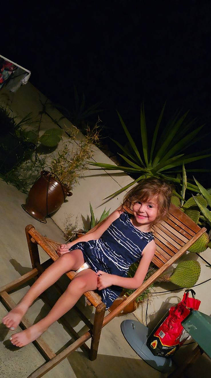 Lyah participe au concours pour gagner de l'argent avec cette photo : barefoot, chair, comfort, flowerpot, foot, fun, grass, houseplant, human_leg, joy, lap, leisure, outdoor_furniture, person, plant, sandal, shorts, sitting, smile, summer