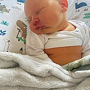 Julius joined the competition — help win amazing prizes! baby, sleeping, blanket, pillow, dinosaur_print, infant, cozy, white_clothing, closeup, child, soft_fabric, peaceful, cute, indoors, portrait, head, face, skin, resting, nap