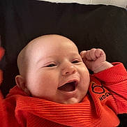 Julius joined the competition — help win amazing prizes! baby, baby_face, cheerful, child, clothing, cute, expression, face, fist, happy, head, indoor, infant, joy, orange_sweater, portrait, sitting, smiling, warm, young_child