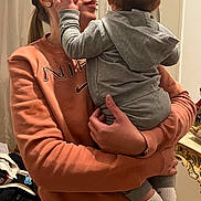 Aylan participe au concours pour gagner de l'argent avec cette photo : adult, affection, baby, back_of_head, casual, child, hand, holding, home, hoodie, hugging, indoor, mirror, nike, portrait, profile_face, socks, stroller, sweatshirt, woman