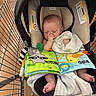 baby, infant, sleeping, shopping_cart, car_seat, blanket, book, toy, bib, thumb_sucking, portrait, indoors, store, retail, safety_labels, face, feet, cozy, colorful, parenting