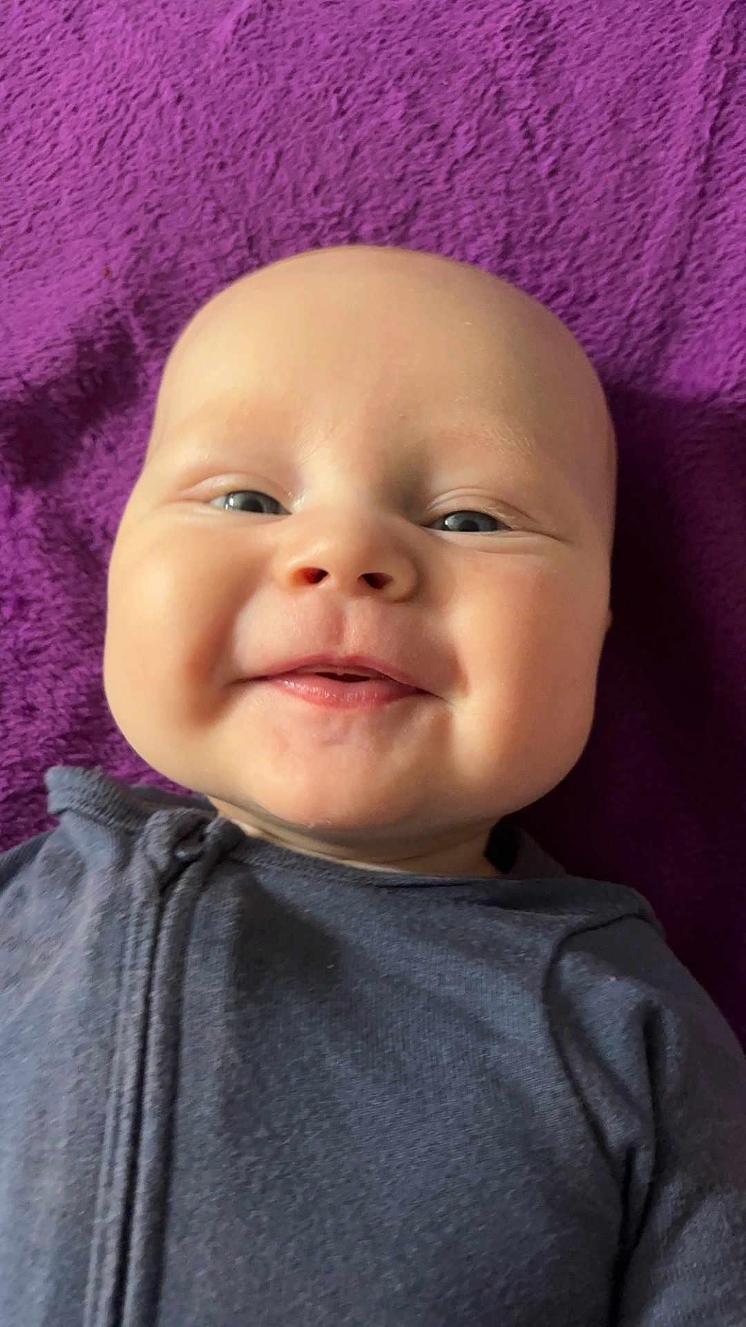 Stetson joined the competition — help win amazing prizes! baby, smiling, face, portrait, child, infant, close_up, happy, cheeks, eyes, clothing, purple_blanket, texture, lying_down, cute, young, skin, head, expression, one_person