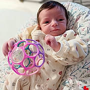 Emmy participe au concours pour gagner de l'argent avec cette photo : baby, infant, onesie, toy, plastic_ball, cushion, patterned_clothing, indoor, closeup, newborn, cute, child, person, soft_toys, hand, face, sleepwear, resting, young_child, comfort