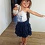 child, girl, indoor, smiling, glasses, plush_toy, bunny, skirt, white_tank_top, sandals, wooden_floor, curtain, door, happy, pose, person, home, flooring, toy, cute