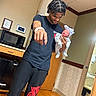 Keisha is registered to the contest to win money with this photo: baby, newborn, man, person, hospital_room, indoor, floor, door, clothing, braided_hair, pajamas, hat, wooden_floor, medical_equipment, smiling, holding, curtain, cabinet, microwave, young_adult