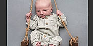 Vinnie is registered to the contest to win money with this photo: baby, infant, swing, wooden_swing, ropes, pajamas, cozy, striped_clothing, barefoot, gray_background, cute, child, portrait, indoor, newborn, seated, hands, feet, wood, baby_clothes